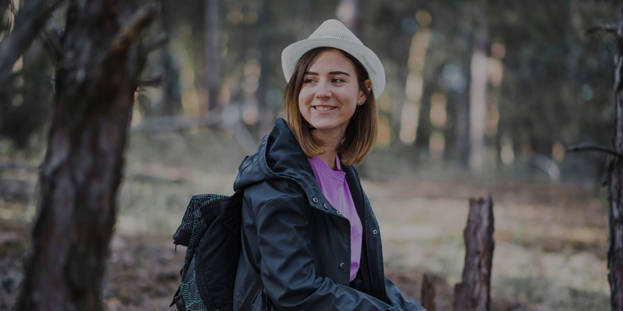 Woman in a forest wearing a hat and raincoat